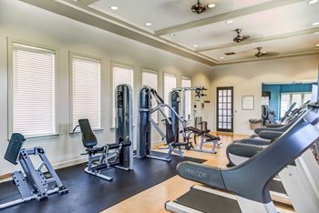 A gym with weights and cardio equipment and windows